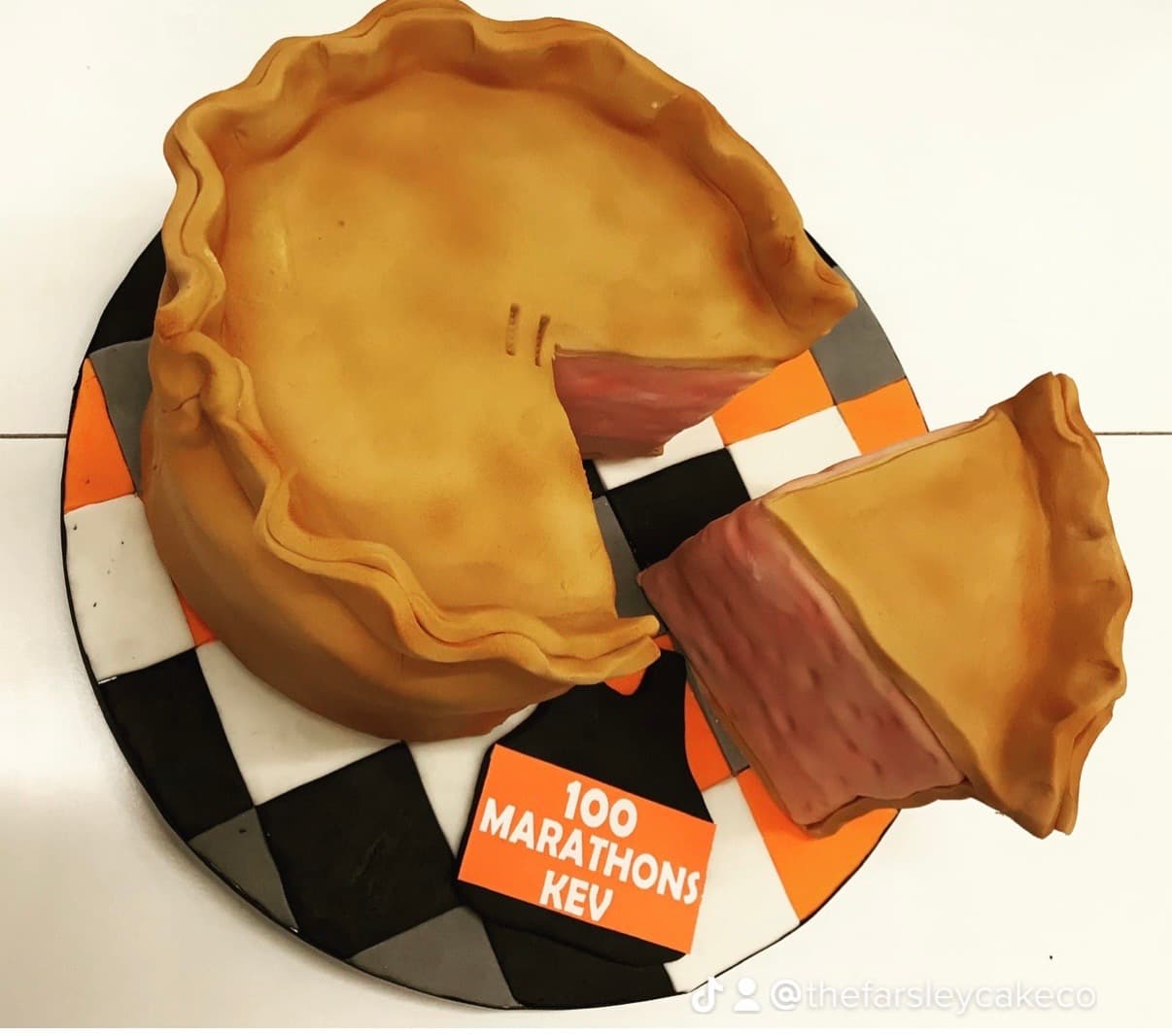 Realistic pie-themed cake with slice on checkered board