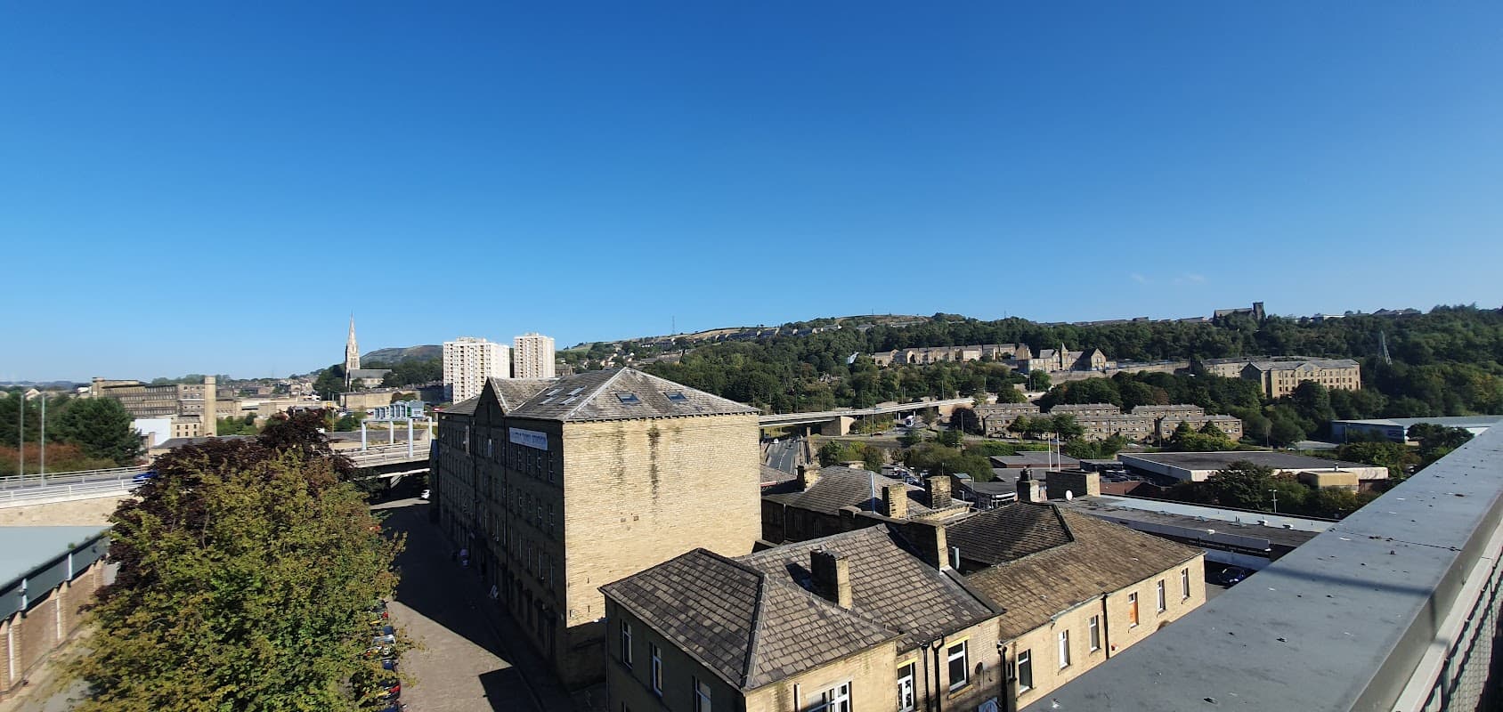 View of Broad Street Plaza car park in Halifax, showcasing buildings, greenery, and a clear blue sky.
