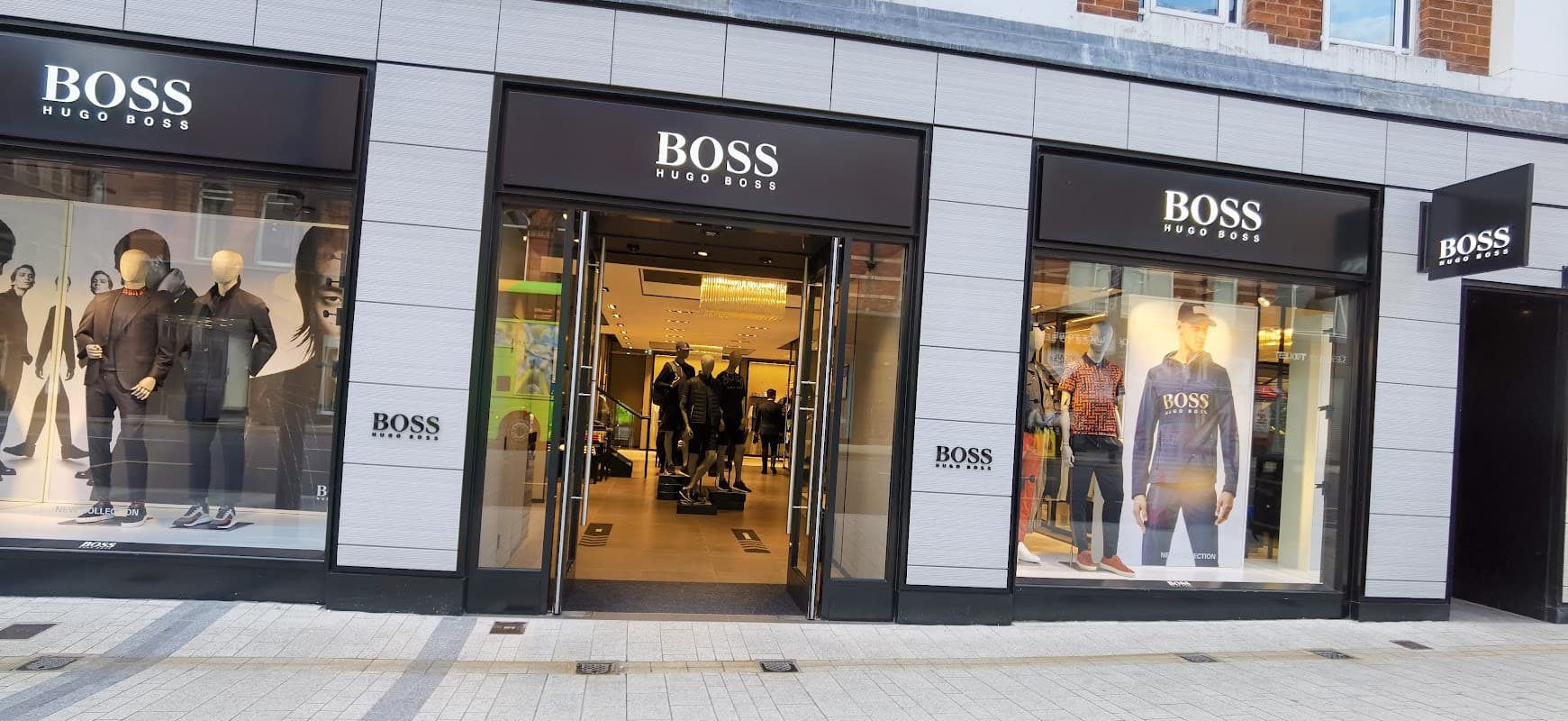 BOSS store entrance featuring stylish mannequins, modern decor, and large glass windows showcasing clothing displays.