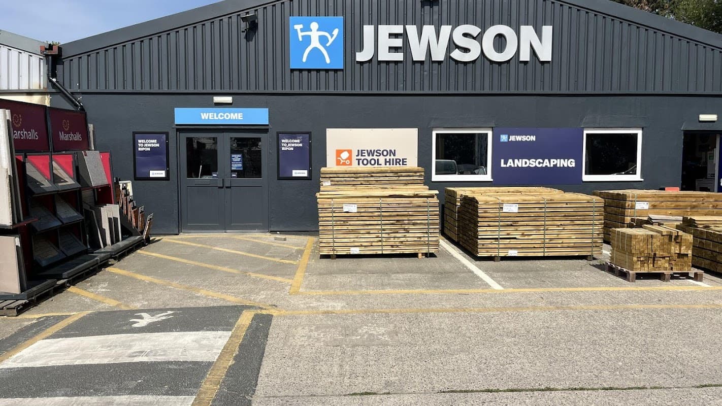 Jewson store front with wooden pallets, signage for tool hire and landscaping, and a welcoming entrance.