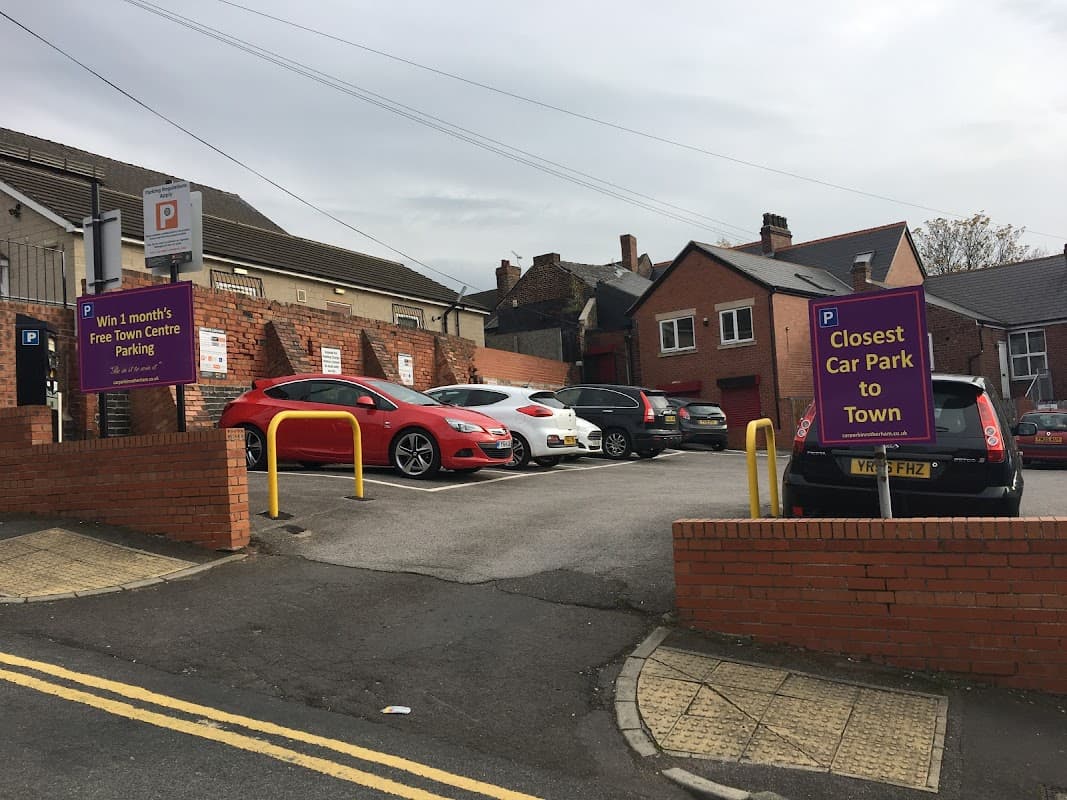 Pay & Display car park with signage, red car, and several parked vehicles in Rotherham, Yorkshire.