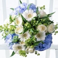 Bouquet of white roses, daisies, and green buds with blue hydrangeas, arranged in a lush, rounded display.